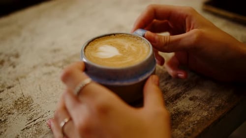 Close Up of Hands Holding Coffee With Heart Foam
