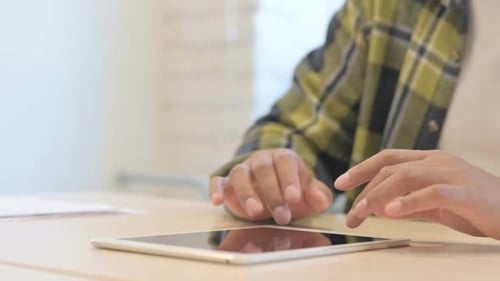 Close Up of African Man Using Tablet Lying on Desk