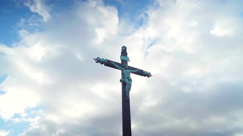 Looking up Jesus cross statue on a cloudy and blue sky, powerful religion and faith symbol