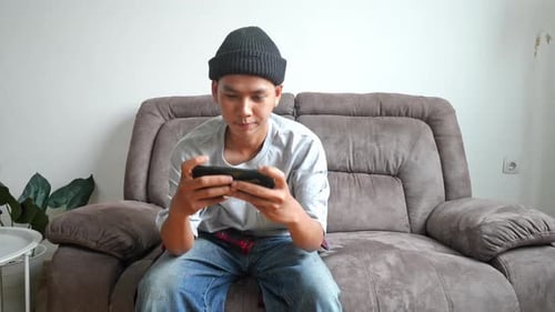 Young Adult on Couch Playing Mobile Game