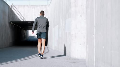 Young man running along city street in slow motion for fitness and healthy lifestyle