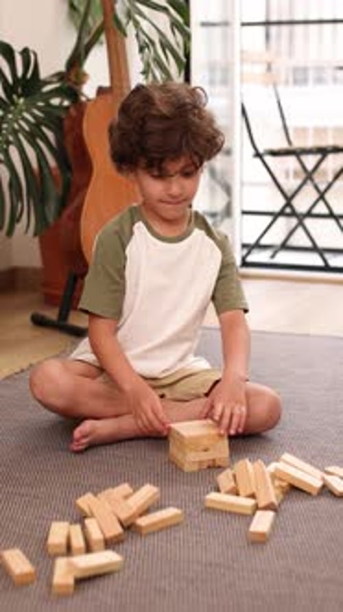 Young Boy Building Wooden Block Tower at Home