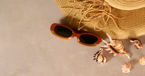 Female straw hat and sunglasses lie on beach sand. Travel summer accessories