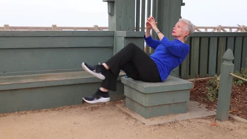 Senior woman exercising at a park by the beach