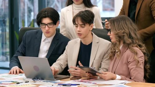Business meeting in an office, workers discussing business affairs using laptop. Papers with charts