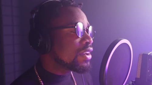 Adult Black Man is Singing Song to Microphone Portrait in Professional Recording Studio or Radio