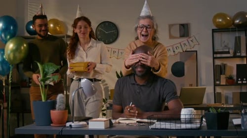 Coworkers Surprise Man at Desk With Birthday Celebration