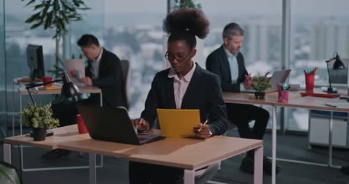 Business woman in office working on laptop and documents