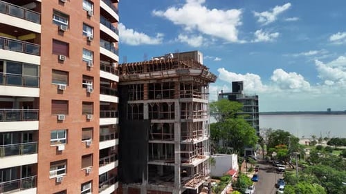 Drone perspective capturing a construction site and completed building side by side, showcasing the