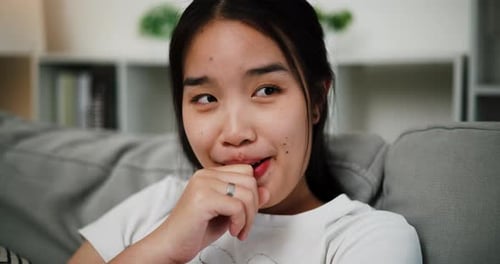 Smiling Young Woman Relaxing on Gray Couch Indoors