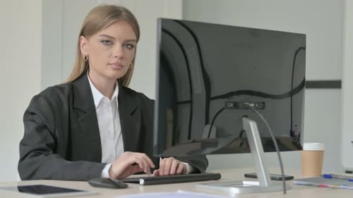 Young Woman Smiling While Working at Computer