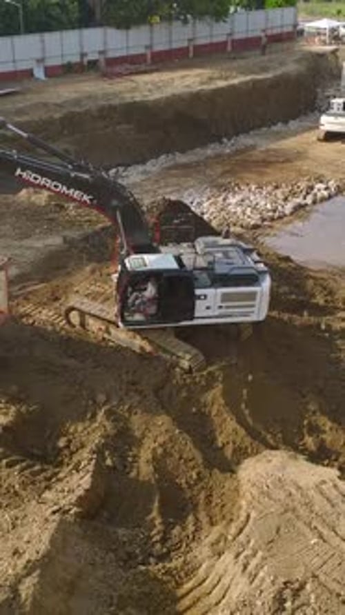 Excavator Digging Dirt at Construction Site, Aerial View