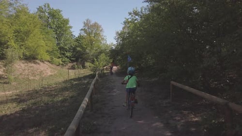 Kids riding bike in a park in the shadow of trees looking for exciting paths for having fun