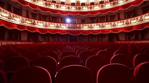 Classic theater hall with empty chairs. Bright spotlight in the red auditorium.