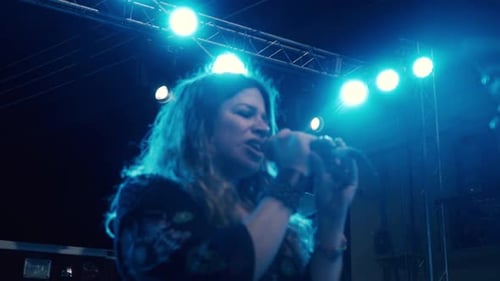 Close up of a female singer, holding the microphone and singing
