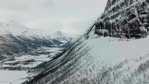 Cinematic Aerial View of Snow Covered Mountain Valley in Winter