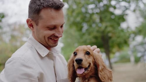 Man and His Cocker Spaniel Puppy Share a Loving Moment at the Park