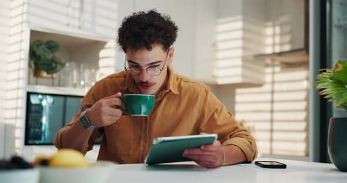 Young Adult Using Tablet While Drinking Coffee