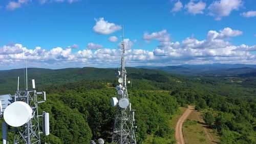 Metal tower with antennas and mobile cells on a hill in the mountain