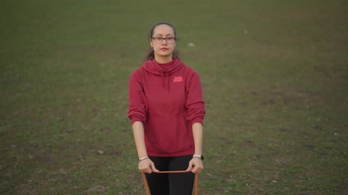 Caucasian Trainer Demonstrating Resistance Band Front View In Park Hands Extended Instructional Pace