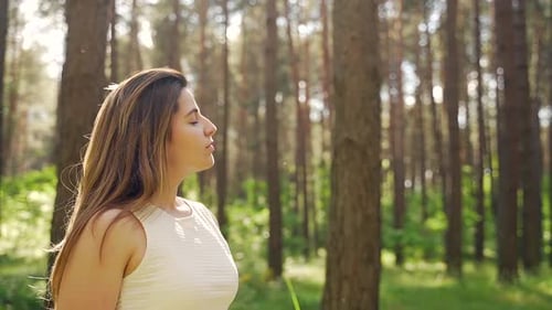 Close up portrait of a pretty young woman breathes fresh air into her full chest in the middle