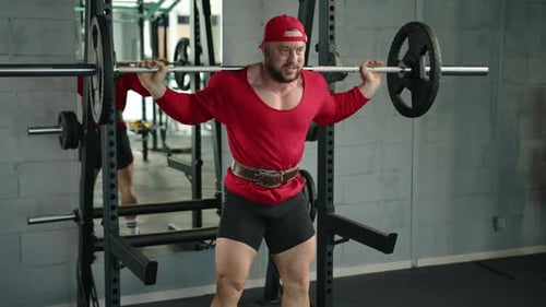 Professional Bodybuilder Squats with a Barbell in the Gym