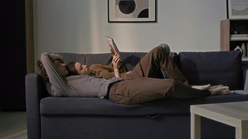 Couple Reading Book Together on Sofa