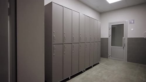 Le vestiaire minimaliste comprend une rangée d'armoires grises propres
