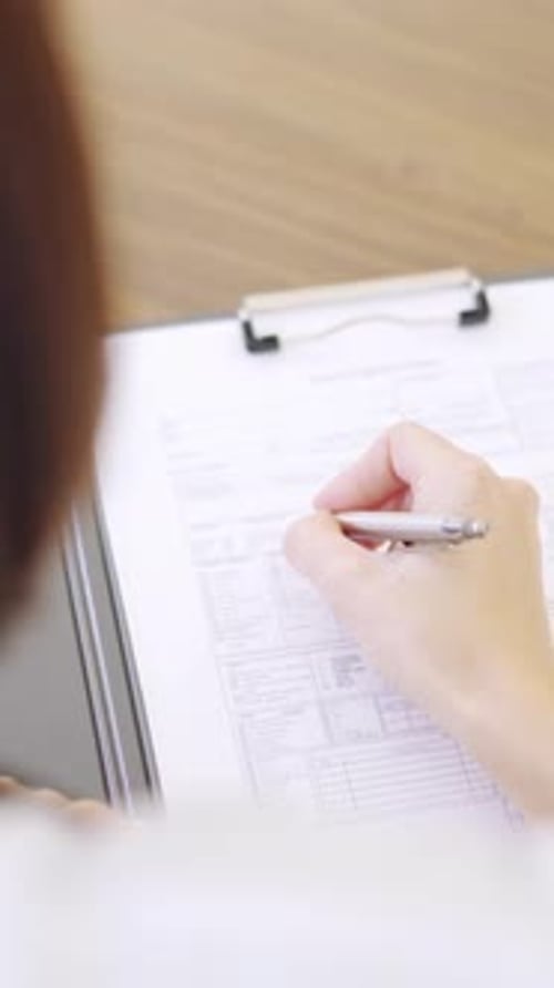 Detail of a Female Doctor Filling a Medical Report