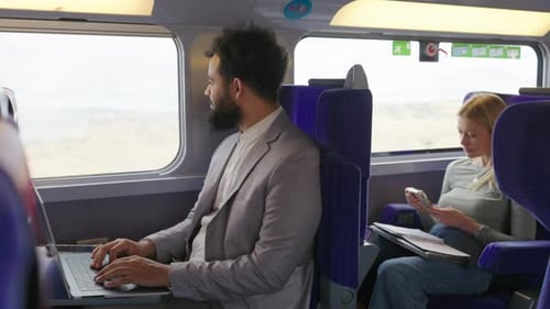 A Business Professional Works on a Train with a Colleague Embodying a Dynamic Busy Lifestyle