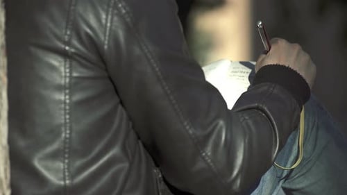 Person Writing in Notebook Outdoors on Sunny Day