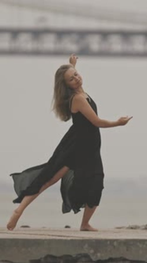 An Adult Woman in Black Dress Dancing on the Pier