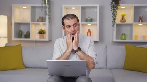 Negative expression of man using laptop.