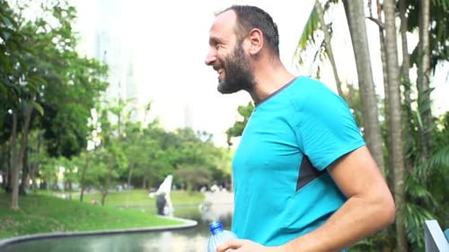 Happy Male Jogger Drinking Water After Workout in City Park, Super Slow