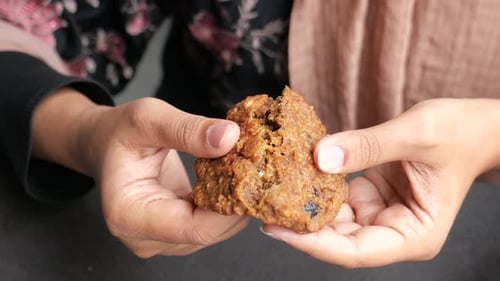 Hands Breaking Oatmeal Raisin Cookie in Half