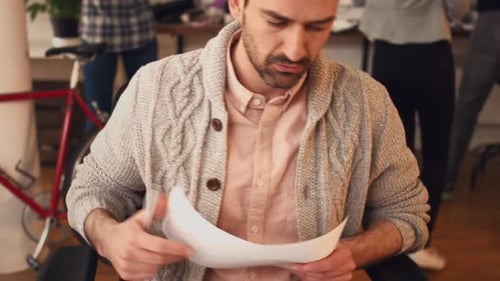 4k video footage of a young designer writing notes while going through blueprints in an office