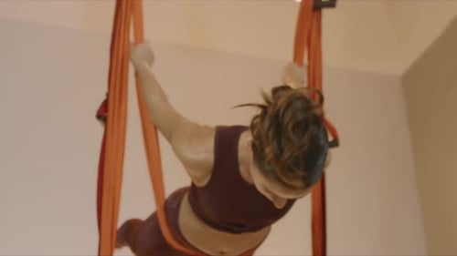 Attractive fitness trainer doing yoga in hammock at aero yoga studio