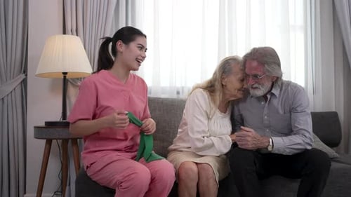 Caring Nurse Helping Senior Couple With Exercises at Home