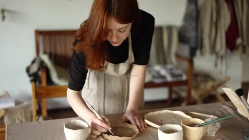 Young Woman Designs Pottery in Home Studio