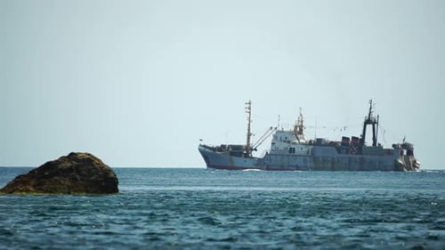 Fishing Boat Trawler Catches Fish While Sailing on Sea A Commercial Fishing Boat on the Horizon in a