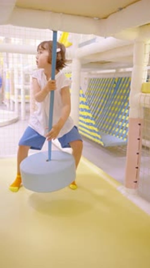 Little girl tries to swing on indoor playground