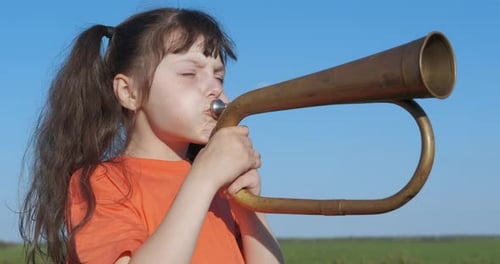 Young Child Blowing a Brass Horn Outdoors