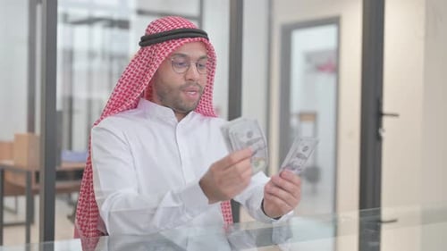 Young Adult Counting Cash in Office Setting