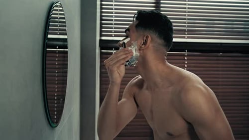 Homem hispânico com vista lateral de perto depila cabelo facial e barba com espuma