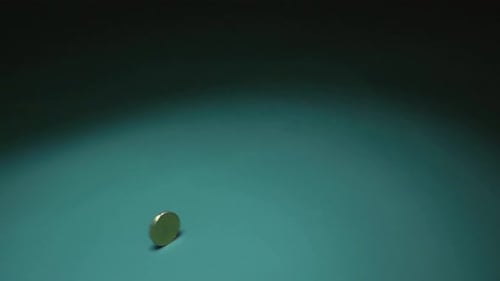 Das Filmmaterial zeigt eine 20-Cent-Euro-Münze, die sich schnell auf einem leuchtend grünen Hintergrund dreht. Die Münze wirbelt herum