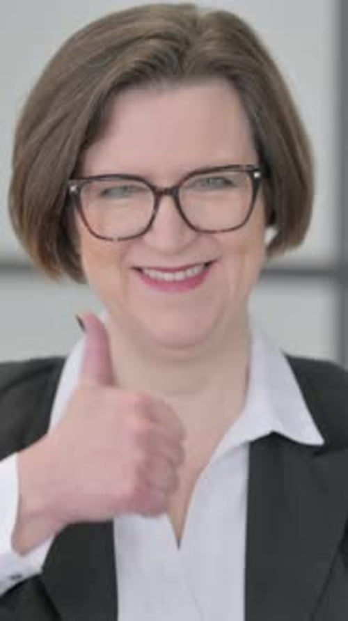 Businesswoman Giving Thumbs Up of Approval in Office