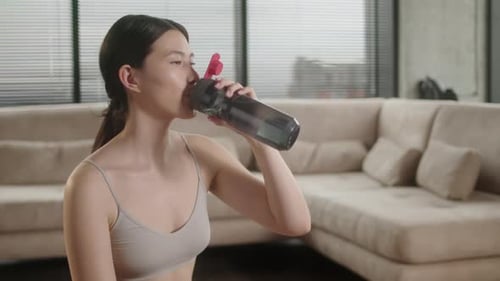 Woman Drinking Water After Exercise at Home