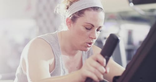 Woman Working Out on Stationary Bicycle in Gym