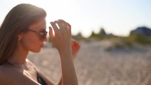Young Attractive Playful Blonde Woman in Swimsuit and Sunglasses Walking on a Sunny Tropical Beach