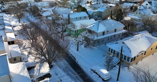 Aerial of American homes in fresh winter snow. USA establishing shot after snowstorm, snowfall. USA